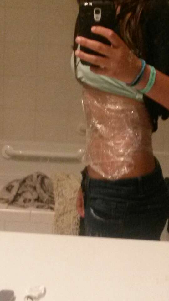 you then just put some lotion on your stomach and on the side of your stomach. Then you wrap the cling wrap around your stomach a couple of time.