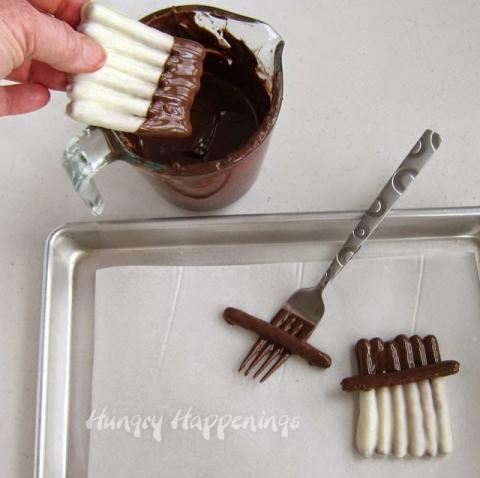 dip the un-coated ends into chocolate
 
Dip one pretzel completely in the chocolate, let it sit a minute to begin hardening. Place it at a slight angle just at the bottom edge of the chocolate dipped pretzels forming the brim of the snowman’s hat. 