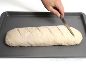 Pinch edge of dough into roll to seal. Roll gently back and forth to taper ends. Place both loaves on cookie sheet.Cut 1/4-inch-deep slashes across tops of loaves at 2-inch intervals with sharp knife. Brush loaves with cold water.