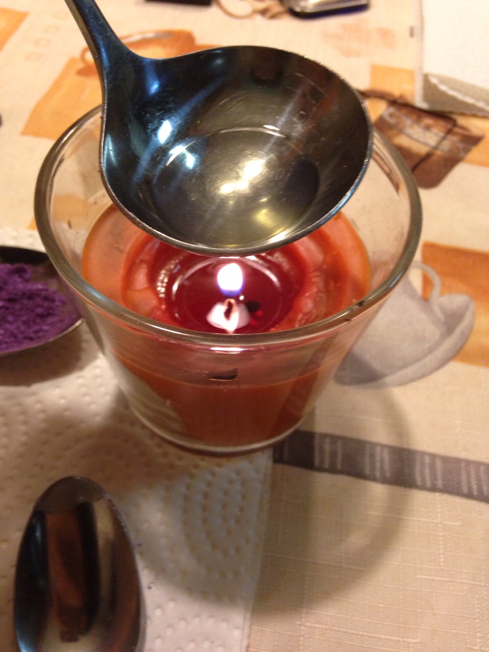Over the candle, melt the Vaseline. (Careful not to let the spoon touch the flame)