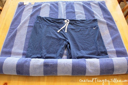 Roll the towel up with the clothing inside it.