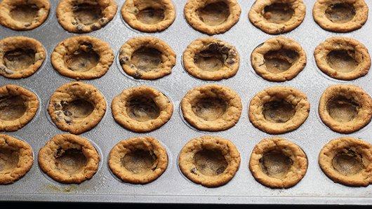 2) Bake 10 to 12 minutes or until golden brown. Remove cookies from oven. Gently press small 1/2 measuring teaspoon or tiny spoon into center of each baked cookie to make shape of cup. Cool in pan 10 minutes.