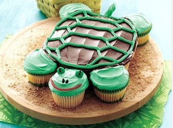 A big cake for the body and cupcakes for the head and arms. Frost the shapes on the back. Licorice mouth and tail. Use gum balls with a line or dot of frosting for the eyes.