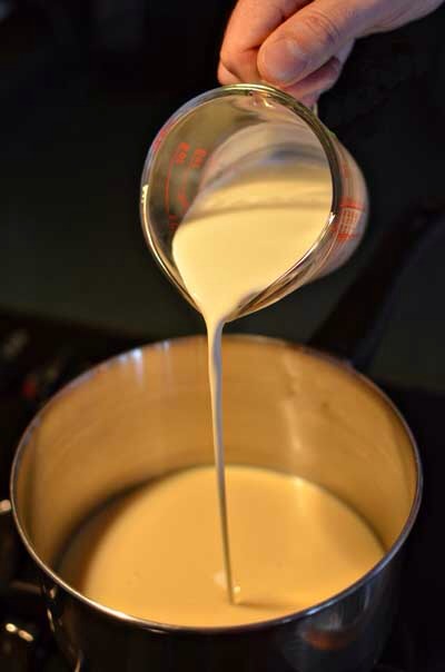 Line an 8″ x 8″ pan with parchment paper. Heat the cream and condensed milk over low heat until steaming.