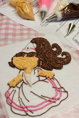 for the initial details, you are better off with an icing bag and a #1 decorating tip if you can get one. 
Now, trace over the outlines that you want to see on your finished product. This bottom layer will be the top layer -- the one you see -- on your design. 