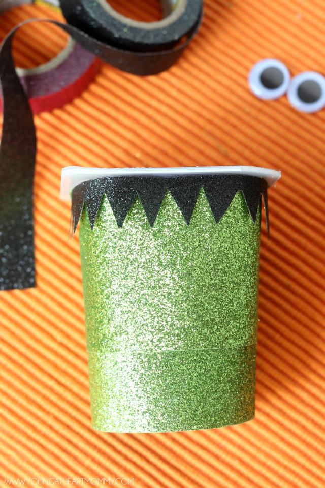 2. To create Frankenstein's hair you will need a strip of black washi tape, cutting a triangle pattern with scissors until the piece is long enough to wrap around the top portion of the cup.
