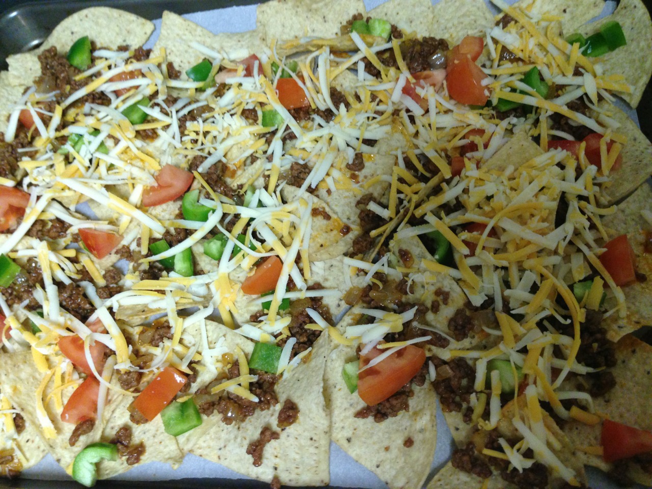 Layer meat, green pepper, tomato and cheese on top of chips