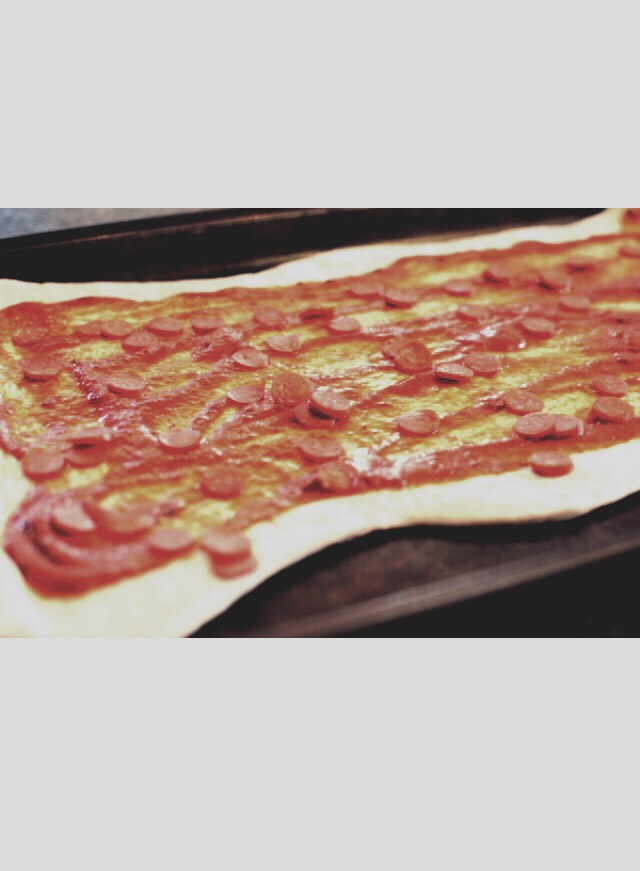 Then sprinkle the entire thing with mini pepperonis. Then cut the dough in half