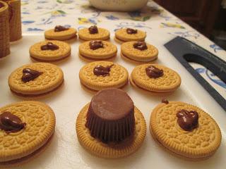 Dot each cookie with some chocolate and place a peanut butter cup upside-down on top.

Dip the bottom of the cone into the chocolate and set on top of the peanut butter cup.