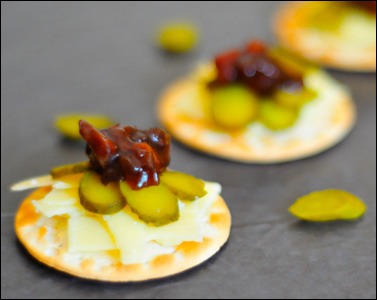 Cheese and pickle canapés - 100kcal (420kJ)

-3 water biscuits: 42kcal (176kJ)
-15g of 30% less fat mature cheddar: 46kcal (193kJ)
-30g gherkin: 4kcal (17kJ)
-6g (1 teaspoon) of pickle: 8kcal (34kJ)