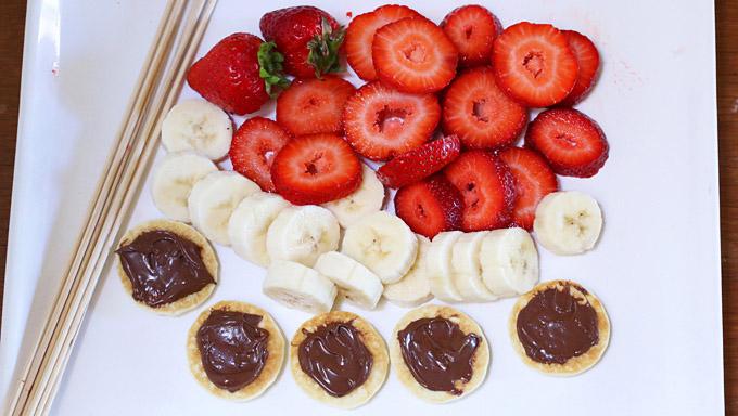 It doesn't get any easier than this. Slice the fruits, smear some Nutella on each of the pancake bites, and layer the ingredients onto the kabob sticks.