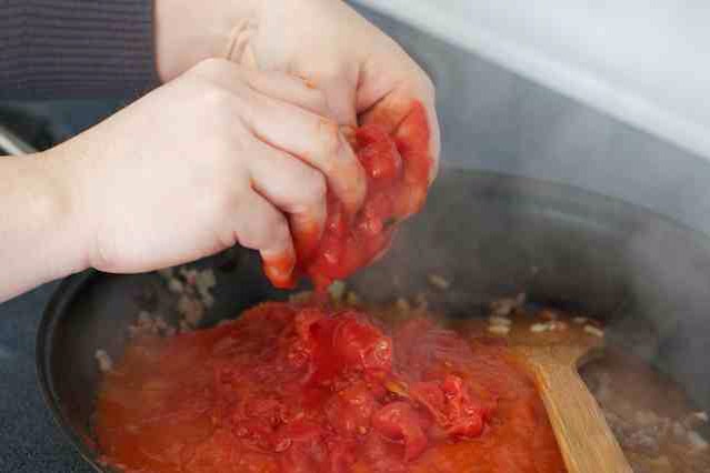 add the tomatoes, crushing the tomatoes with your hands