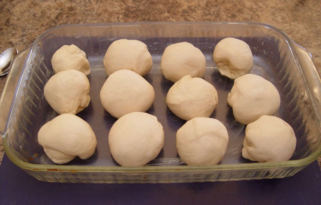 10. Gently round them into balls, and put them in your buttered 9×13 pan.
11. Put the pan into your warm 170 degree oven. Let them rise for about 20 minutes or until they have risen an 1 inch above the rim of the pan.