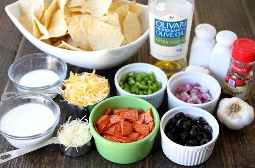 To make the Pizza Nachos, you will need: butter, olive oil, garlic, heavy cream, milk, salt, pepper, red pepper flakes, Parmesan cheese, tortilla chips, onion, pepperoni, black olives, green pepper, and Colby Jack cheese.