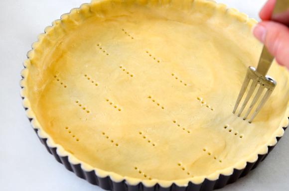 Transfer the dough into the tart pan, and then using your fingers, press it into the pan in an even layer to form the base and sides of the tart crust. Using a fork, prick all over the bottom of the crust. Cover with plastic wrap and freeze for 15 minutes. Preheat the oven to 425 degrees.