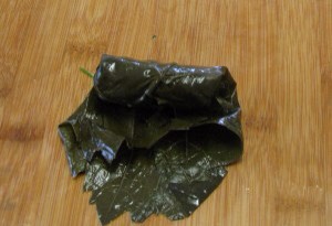Next fold both sides inward lengthwise and then tightly roll leaf toward pointed tip end to make like a closed cigar/burrito.