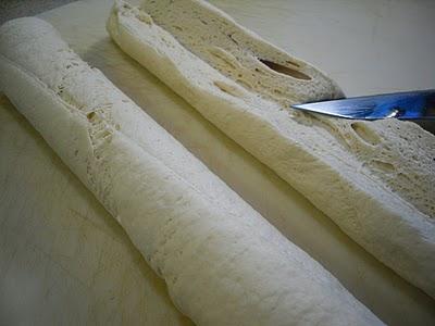 Place bread dough, seam sides up on a cutting board.  Slice each loaf lengthwise, end to end, cutting halfway through to center of loaf.