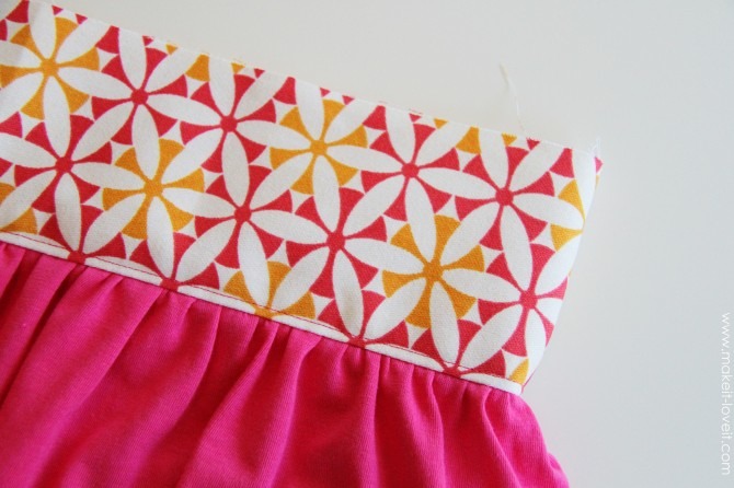 Next, flip that top strip of fabric up & iron open. Be sure that the fabric flap from behind (the seam allowance) is ironed upwards.  Then sew a seam right at the bottom of the strip of fabric you just attached, making sure that the seam allowance from behind is included in the seam.  
