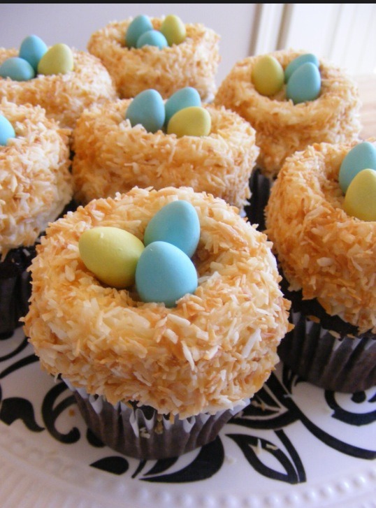 Leave a grove in the frosting for the eggs. On a plate put toasted coconut shavings. Roll the cupcake in the coconut. Place chocolate eggs in the grove. 