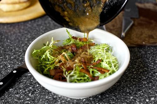 Add shallot to bacon fat and cook for one minute, stirring. Add red wine vinegar and let hiss and bubble for 20 to 30 seconds, then remove from heat and whisk in Dijon. Immediately pour hot dressing over frisée and toss with drained lardons, salt and pepper.
