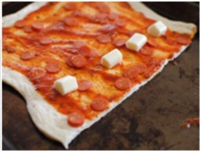 Place the mozzarella strong pieces in a row, and sprinkle some of the shredded mozzarella too.