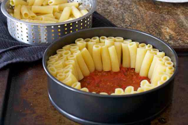 Tightly place the cooked pasta in the pan, standing the pasta up