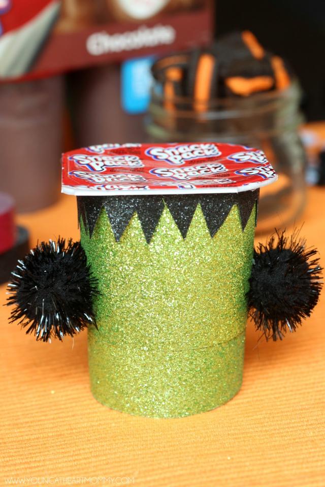 3. Use a hot glue gun and attach one black pom pom on each side of the cup. These will act as bolts.