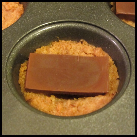 Step 3:
While the crust is in the oven, break two of the candy bars into rectangles. Remove pan from oven; place one rectangle into each cup.