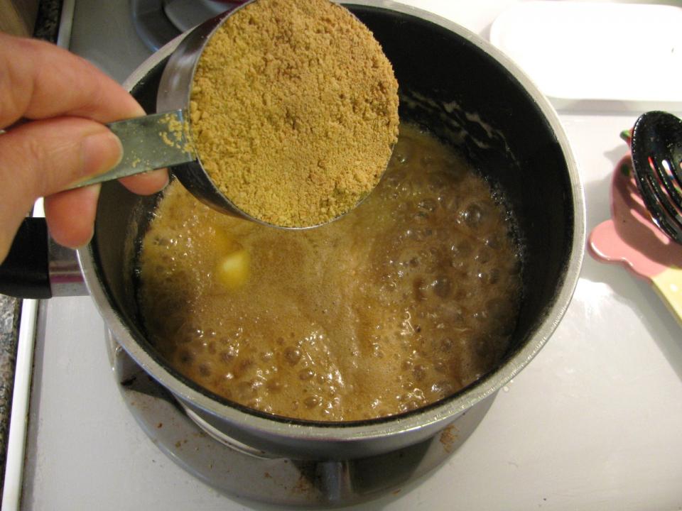 Add the crushed graham crackers to the melted butter and sugar mixture.