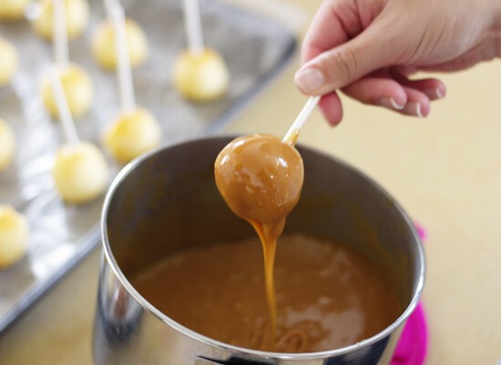 Unwrap the caramels and melt them in a pot over medium-low heat, with 2 Tbsp of milk. You can buy bags of caramel bits too if you don't want to go through the trouble of unwrapping them. Once the caramel is smooth and melted, remove it from heat and dip the apple pops one by one, letting the excess 