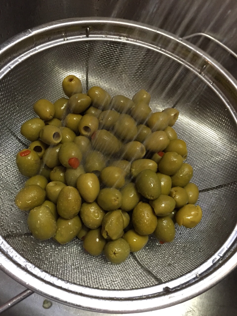 Preparing your olives while the meat is simmering for 45 min. 

Drain olives into colander. 