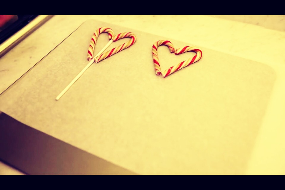 Place Popsicle stick in between the two candy canes on the parchment paper.