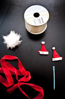 These are the supplies that we used but you can find anything that works for you.  There is red ribbon, a plastic yarn needs. some extra large white wire-ribbon, and a white puff ball that we've glued to a hair pin. 