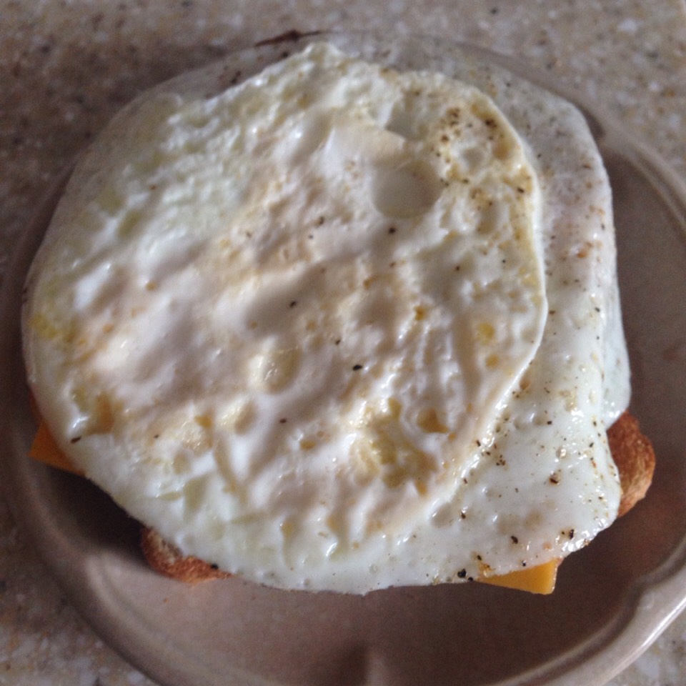 While the bread is toasting cook the egg. I seasoned it with salt and pepper. 
You could also undercook the yolk if you like it that way or even take the yolk out and just use the egg white (that's the healthiest way).
Put a cheese slice on the bread and add the egg right onto it to make it melt.