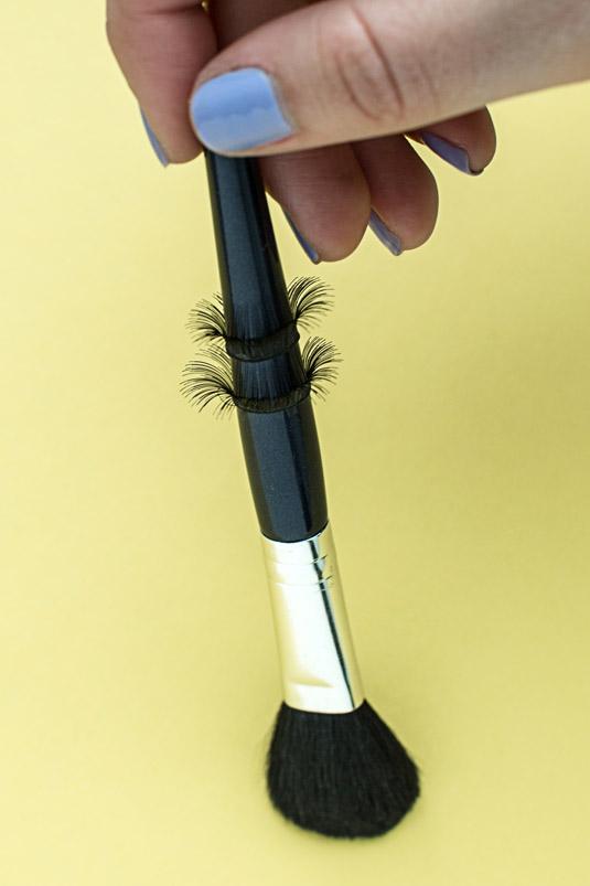 21. Wrap your false lashes around the handle of a makeup brush to give the strips some curve. That way, they'll form to the shape of your eye more easily.