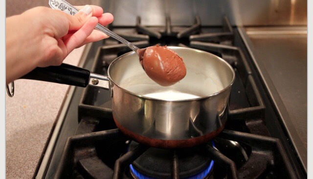 Take out your saucepan. Pour about 1/4 cup of the milk into the saucepan. Then, add about 2 spoonfuls of Nutella. If you like your hot chocolate sweet, then you may add some more, and if you don't like it as sweet, then you can use less. Put the stove on medium-low heat.