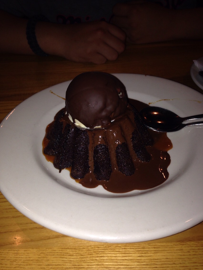 Molten chocolate lava cake topped with vanilla ice cream and a chocolate shell.