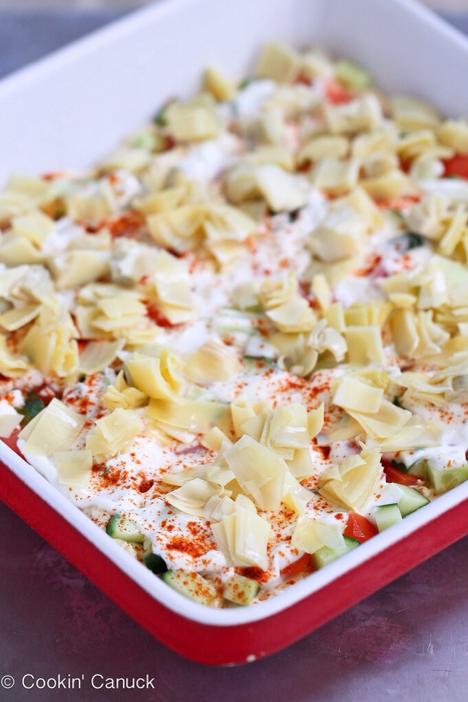 -> Dollop the yogurt over the vegetables, then gently spread with a rubber spatula. Sprinkle the yogurt with salt and paprika.
-> On top of the yogurt, layer the artichoke heart, roasted red peppers and feta cheese. Sprinkle the parsley over top and garnish with olives.