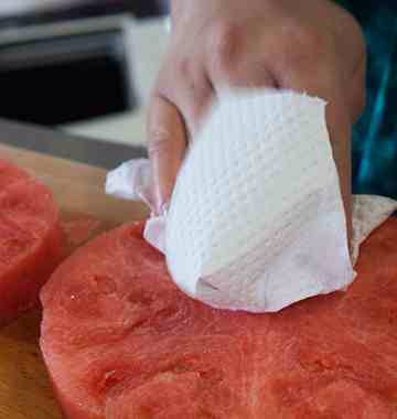 Pat a slice of watermelon dry with a paper towel and place on a serving plate.