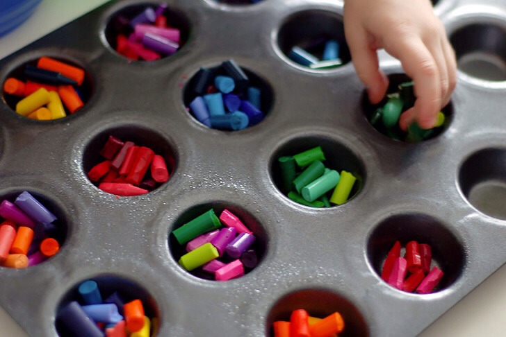 Next step – oil muffin pan liberally (or place paper cups) to have no problem with getting cookies easily out after they have already melted. If the broken crayons are too big for the muffin pan, help yourself with a knife to cut them into the smaller pieces which will fit in.
