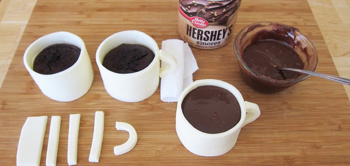 Roll the remaining fondant to 1/4 inch thickness. Cut into 2 1/2 inch by 3/8 inch strips. Bend into a curved coffee cup handle. Brush the ends lightly with water. Press handles onto the sides of each coffee cup. Use some rolled up paper towels to hold the handles in place until they dry.