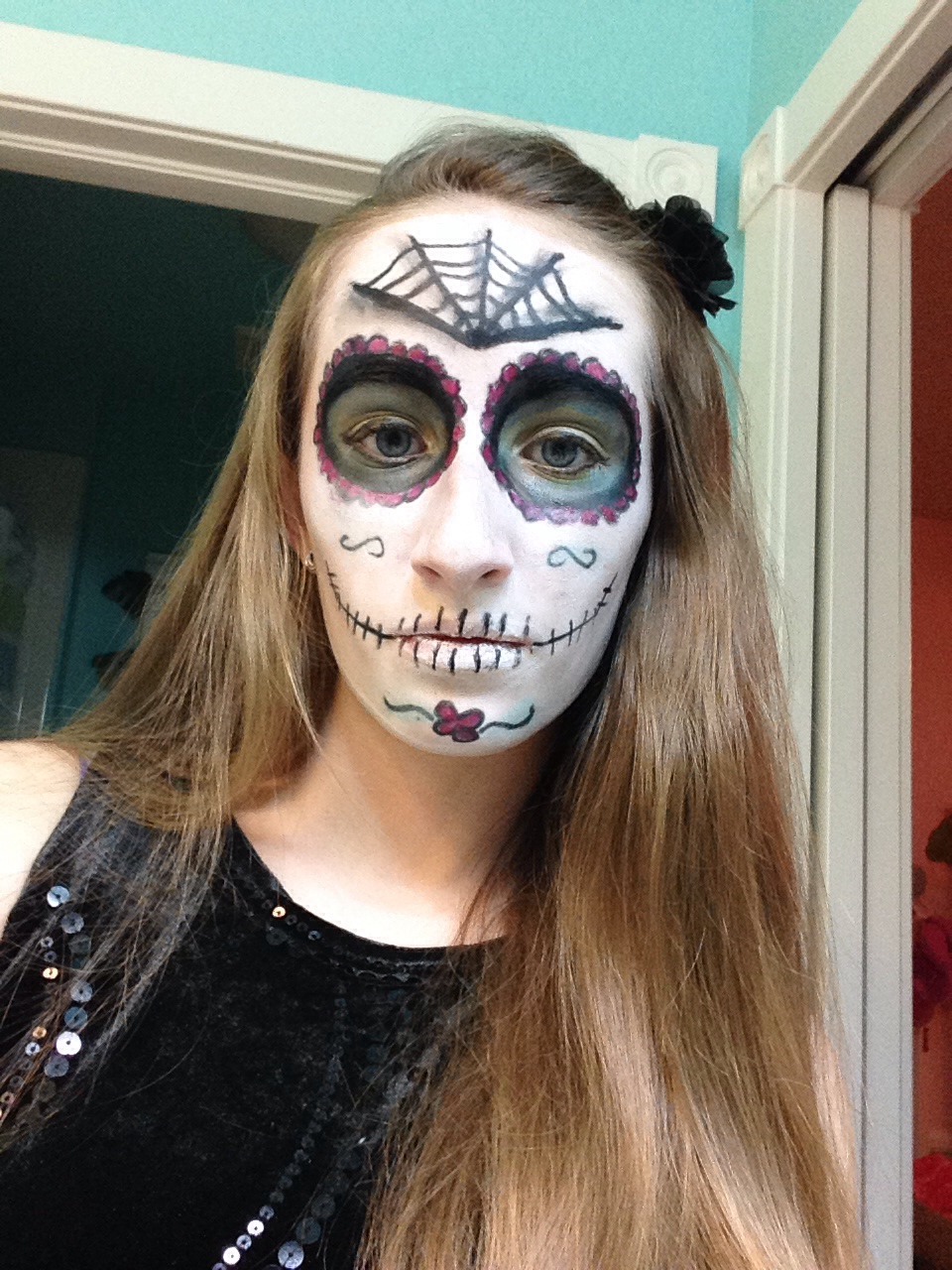 Use black liner to add petals around the eyes and fill in with a color of your choice. Is the liner to add a swirly pattern to your cheekbones and a flower on your chin. Use eyeshadow to go over lines and fill in. Add teeth across your lips and cheeks. Add a spiderweb pattern to your forehead.