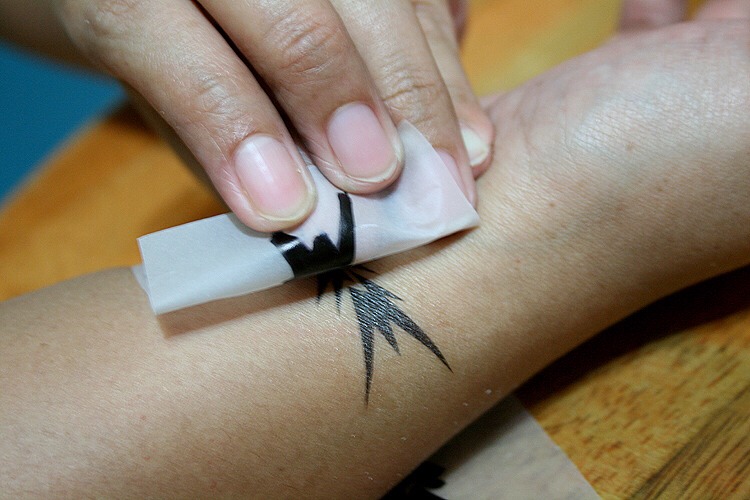 Step 5: Slowly and gently peel up a corner of the paper to see if it is completely transferred to your skin. If not, you'll need to leave the cloth on the design for a few more seconds, then peek again.