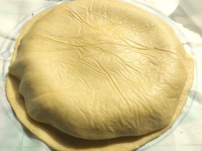 8. Sprinkle the filling with grated Parmesan.

9. Now, cover with the second circle of dough.
10. Seal the edges with your hands, and then use a fork to press.


