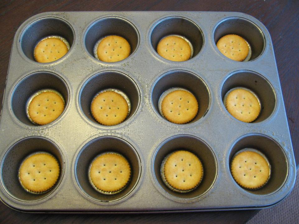 Spray the muffin tins with some non-stick cooking spray.  Place a ritz crackers in the bottom of each one