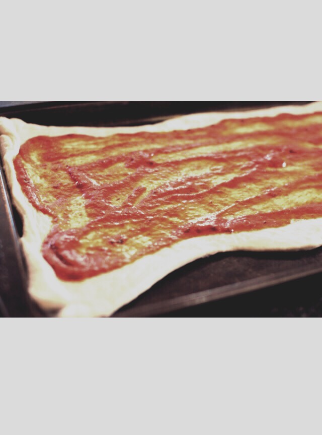 Next, spread about 1/2 a jar of pizza sauce over the entire pizza dough, leaving about an inch around the edges.