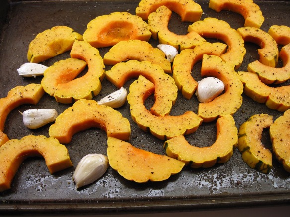 4. Put the squash and garlic cloves on a rimmed baking sheet. Drizzle with the olive oil and toss to distribute the oil. Sprinkle with salt and pepper.