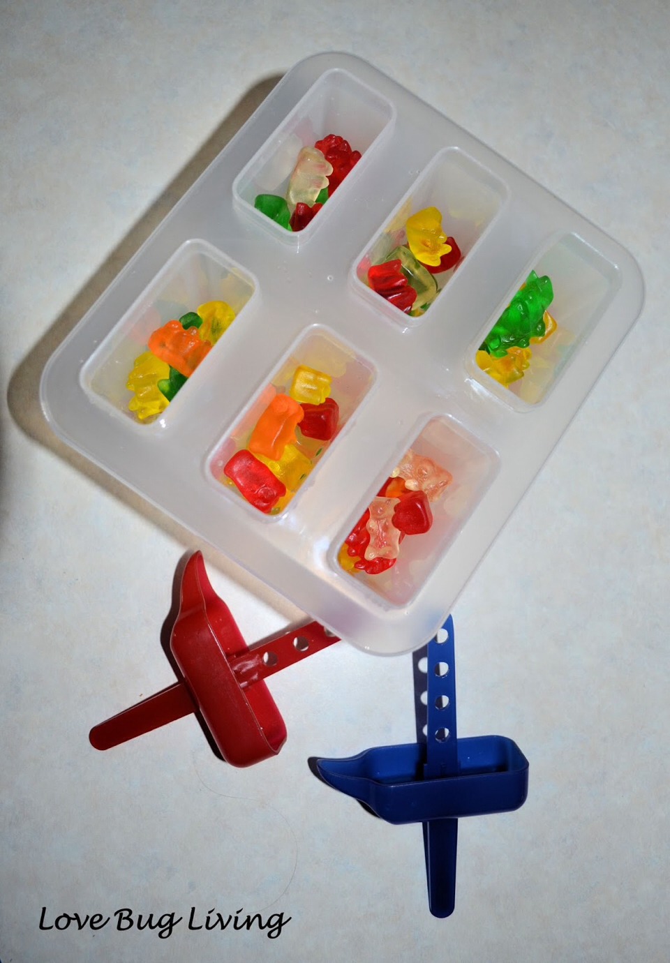 Put as many gummy bears in the Popsicle containers as pleased.