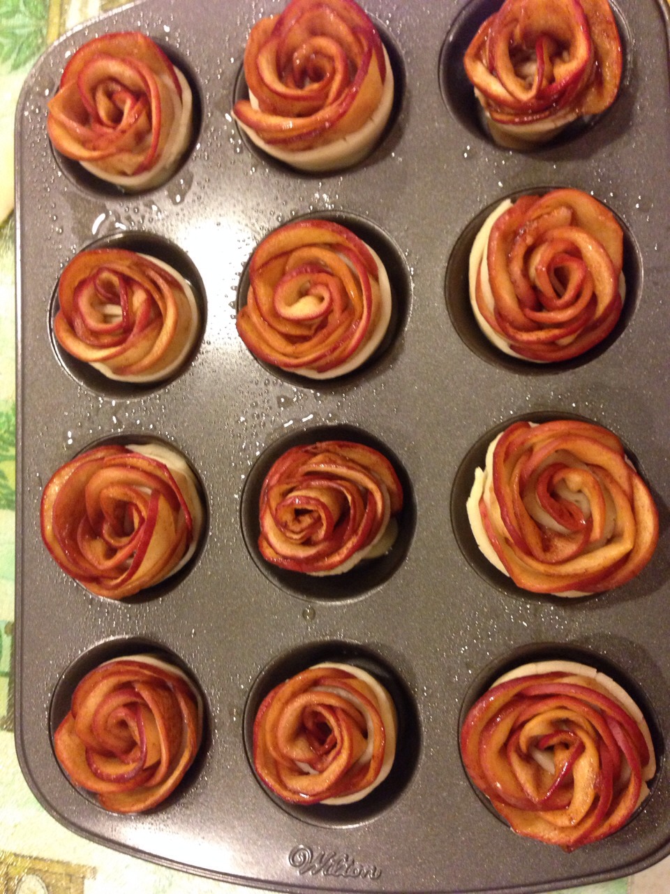 Place them in the cupcake tins after spraying with vegetable oil.
Bake for 15 mins at 325. 
You can brush the tops with the cinnamon sugar mixture to keep the apples from drying out.