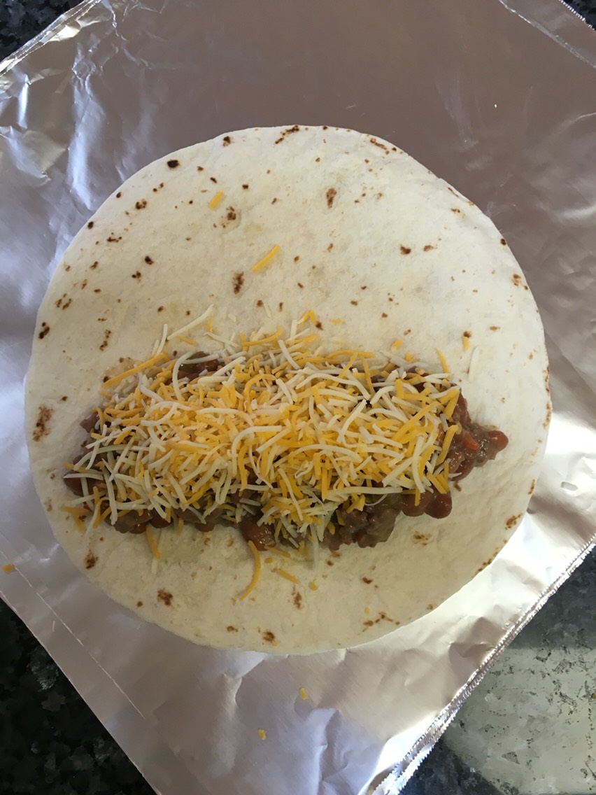 Next cut yourself some foil squares (wrap in foil to freeze that way you always have an easy on the go meal).
Get your flour tortillas ready to just grab, fill, roll & wrap.
In each tortilla, depending on the size, put 2-3 good tablespoons of filling topped with a handful of shredded cheese.